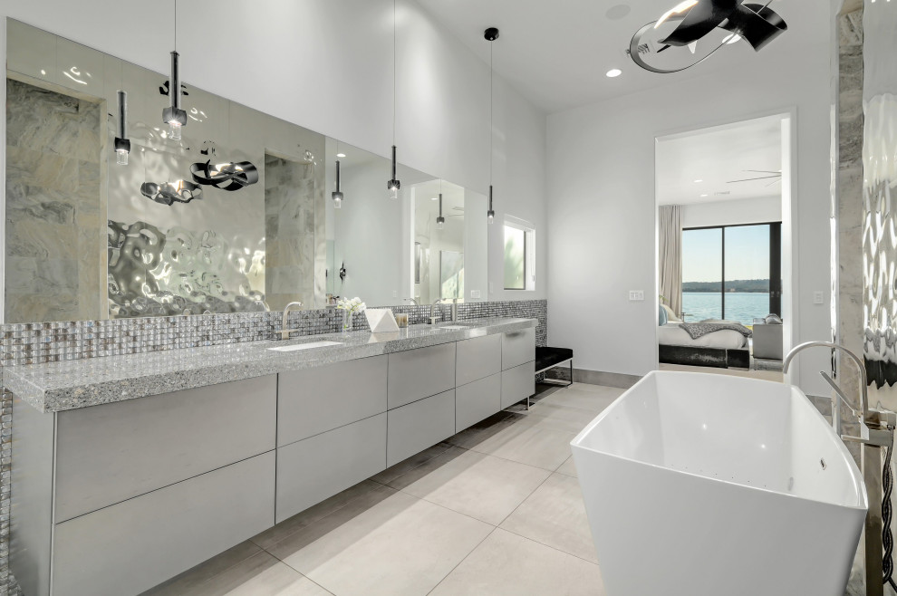 Example of a trendy gray tile and mosaic tile gray floor and double-sink freestanding bathtub design in Austin with flat-panel cabinets, gray cabinets, white walls, an undermount sink, gray countertops and a freestanding vanity