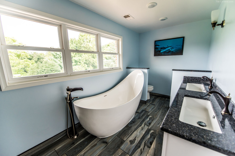 This is an example of a mid-sized transitional master bathroom in DC Metro with beaded inset cabinets, white cabinets, a freestanding tub, blue walls, porcelain floors, an undermount sink, terrazzo benchtops and brown floor.