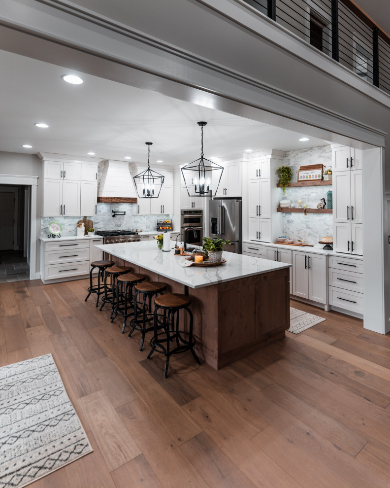 Inspiration for a large farmhouse l-shaped light wood floor open concept kitchen remodel in Other with an undermount sink, shaker cabinets, white cabinets, quartz countertops, multicolored backsplash, marble backsplash, stainless steel appliances, an island and white countertops