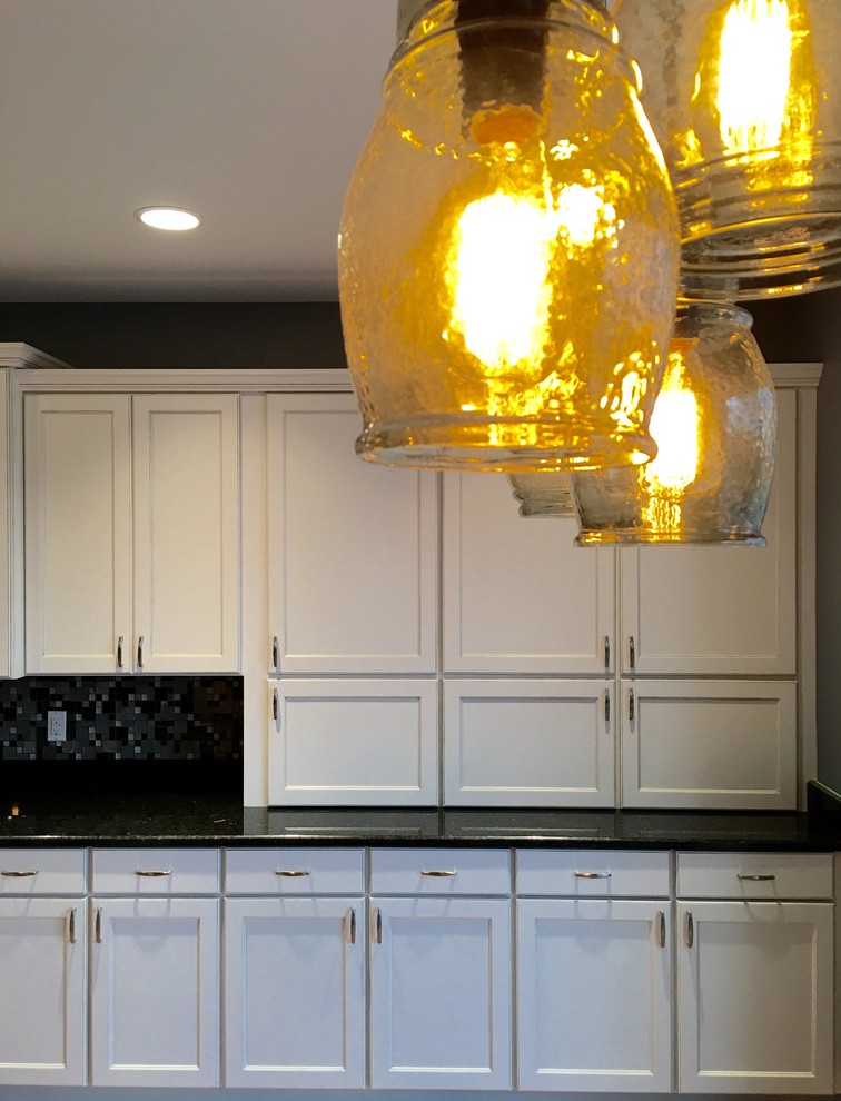 Eat-in kitchen - large transitional l-shaped light wood floor eat-in kitchen idea with an undermount sink, recessed-panel cabinets, white cabinets, granite countertops, multicolored backsplash, glass tile backsplash, stainless steel appliances and an island