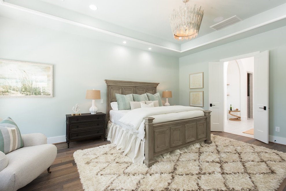 This is an example of a large beach style master bedroom in Houston with green walls, medium hardwood floors, no fireplace and brown floor.