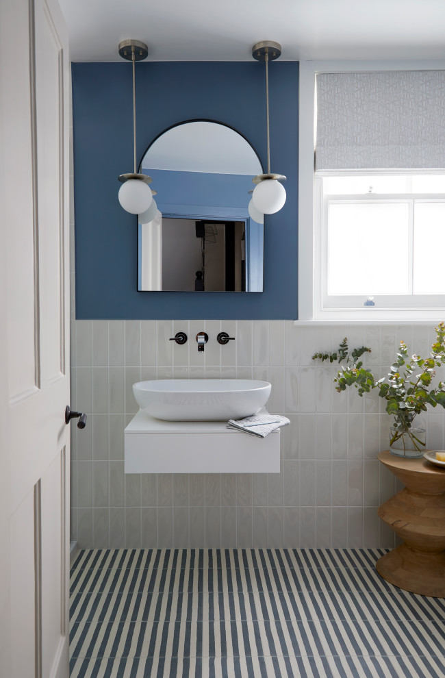 Стильный дизайн: ванная комната среднего размера в современном стиле с подвесной раковиной, синим полом, плоскими фасадами, белыми фасадами, бежевой плиткой, керамической плиткой, синими стенами, полом из цементной плитки, тумбой под одну раковину и подвесной тумбой - последний тренд