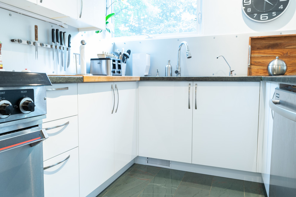Open concept kitchen - mid-sized modern l-shaped ceramic tile and green floor open concept kitchen idea in Toronto with an undermount sink, flat-panel cabinets, white cabinets, granite countertops, gray backsplash, metal backsplash, stainless steel appliances, a peninsula and green countertops