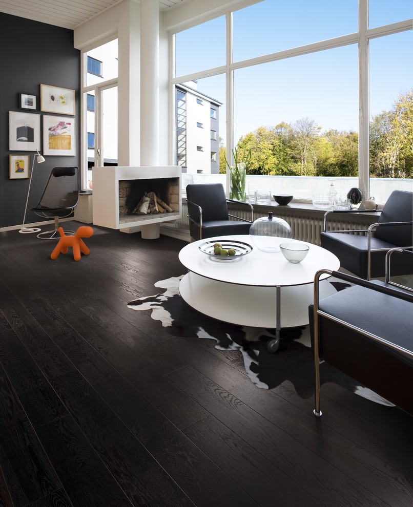 Large midcentury open concept living room in Denver with dark hardwood floors, a hanging fireplace and black walls.