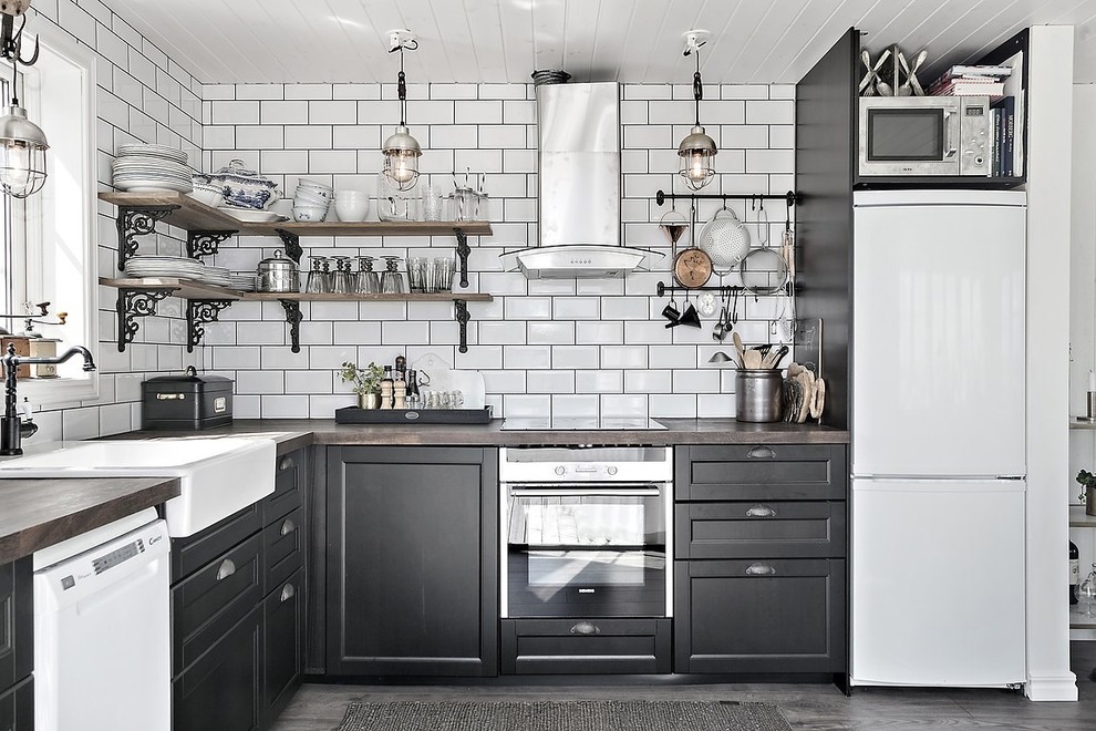 This is an example of a mid-sized country l-shaped separate kitchen in Gothenburg with recessed-panel cabinets, black cabinets, wood benchtops, white appliances and no island.