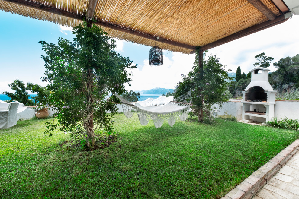 Ejemplo de patio mediterráneo de tamaño medio en patio delantero con adoquines de piedra natural y pérgola