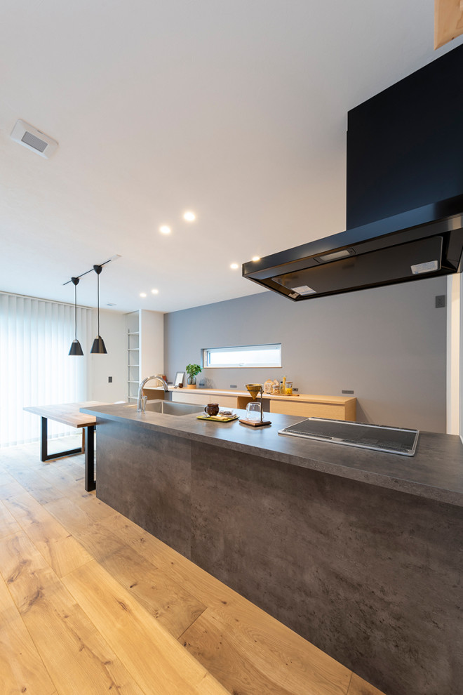 Modern single-wall open plan kitchen in Tokyo with a submerged sink, beaded cabinets, grey cabinets, laminate countertops, white splashback, medium hardwood flooring, brown floors and grey worktops.