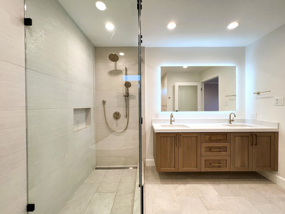 This is an example of a large midcentury ensuite bathroom in San Francisco with shaker cabinets, brown cabinets, a freestanding bath, a corner shower, a one-piece toilet, beige tiles, porcelain tiles, white walls, porcelain flooring, a submerged sink, engineered stone worktops, beige floors, a sliding door, white worktops, a wall niche, double sinks and a floating vanity unit.