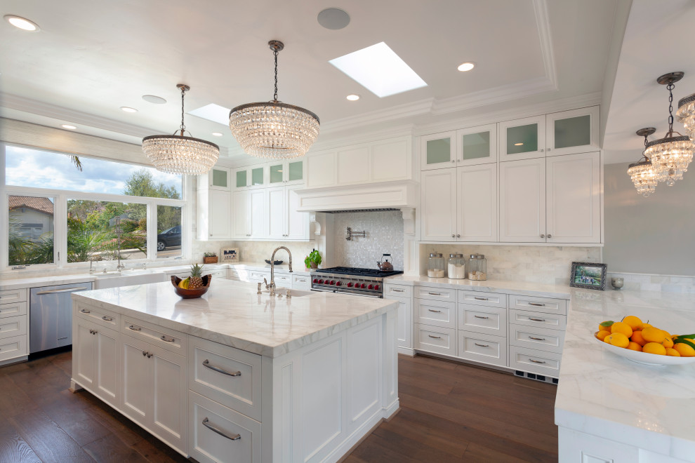 Design ideas for an expansive transitional u-shaped eat-in kitchen in Santa Barbara with white cabinets, white splashback, stainless steel appliances, with island, brown floor, white benchtop, an undermount sink, raised-panel cabinets, marble benchtops, marble splashback, medium hardwood floors and coffered.