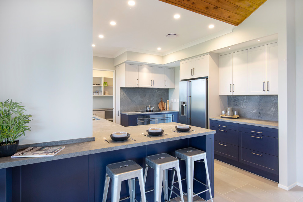 This is an example of a mid-sized country u-shaped separate kitchen in Hamilton with a double-bowl sink, shaker cabinets, blue cabinets, concrete benchtops, grey splashback, stainless steel appliances, ceramic floors, a peninsula, grey floor and grey benchtop.