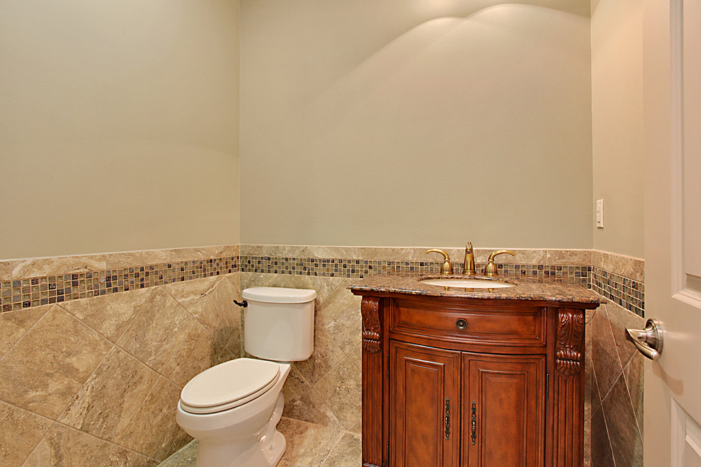 Inspiration for a traditional powder room in New Orleans with an undermount sink, furniture-like cabinets, medium wood cabinets, granite benchtops, beige tile, ceramic tile, beige walls and ceramic floors.