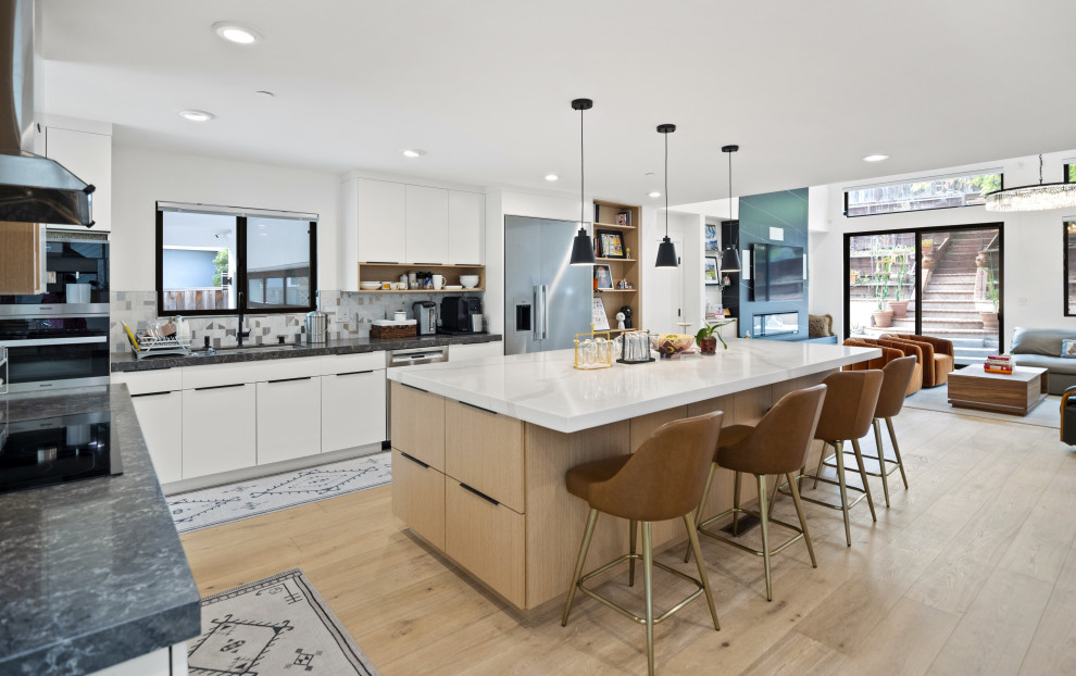 Inspiration for a large modern eat-in kitchen in San Francisco with a drop-in sink, flat-panel cabinets, light wood cabinets, grey splashback, glass tile splashback, stainless steel appliances, light hardwood floors, with island, yellow floor and white benchtop.