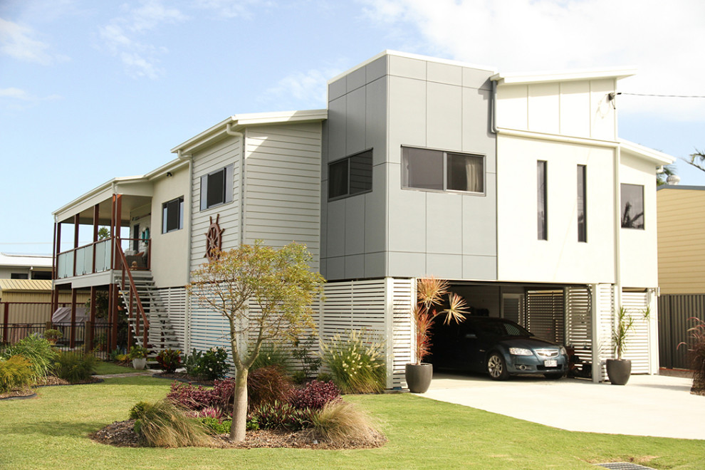 This is an example of a mid-sized beach style two-storey grey apartment exterior in Brisbane with mixed siding, a shed roof and a metal roof.