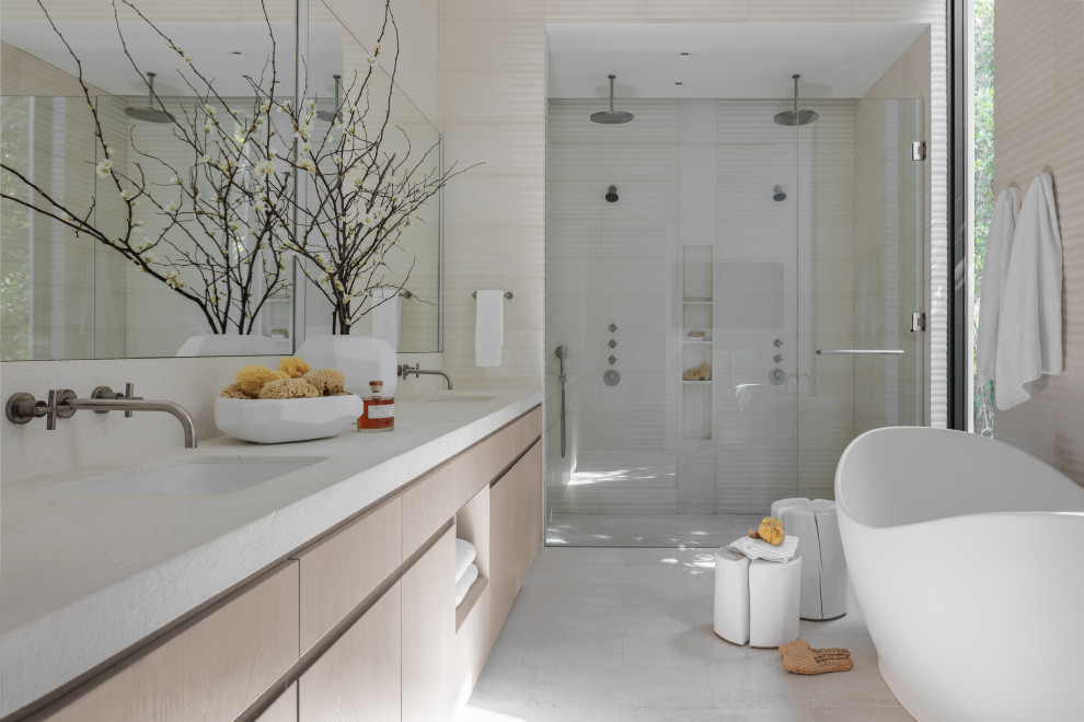 This is an example of a large modern master bathroom in Miami with raised-panel cabinets, light wood cabinets, a freestanding tub, a curbless shower, white tile, limestone, white walls, limestone floors, an integrated sink, marble benchtops, white floor, a hinged shower door, white benchtops, a niche, a double vanity and a floating vanity.