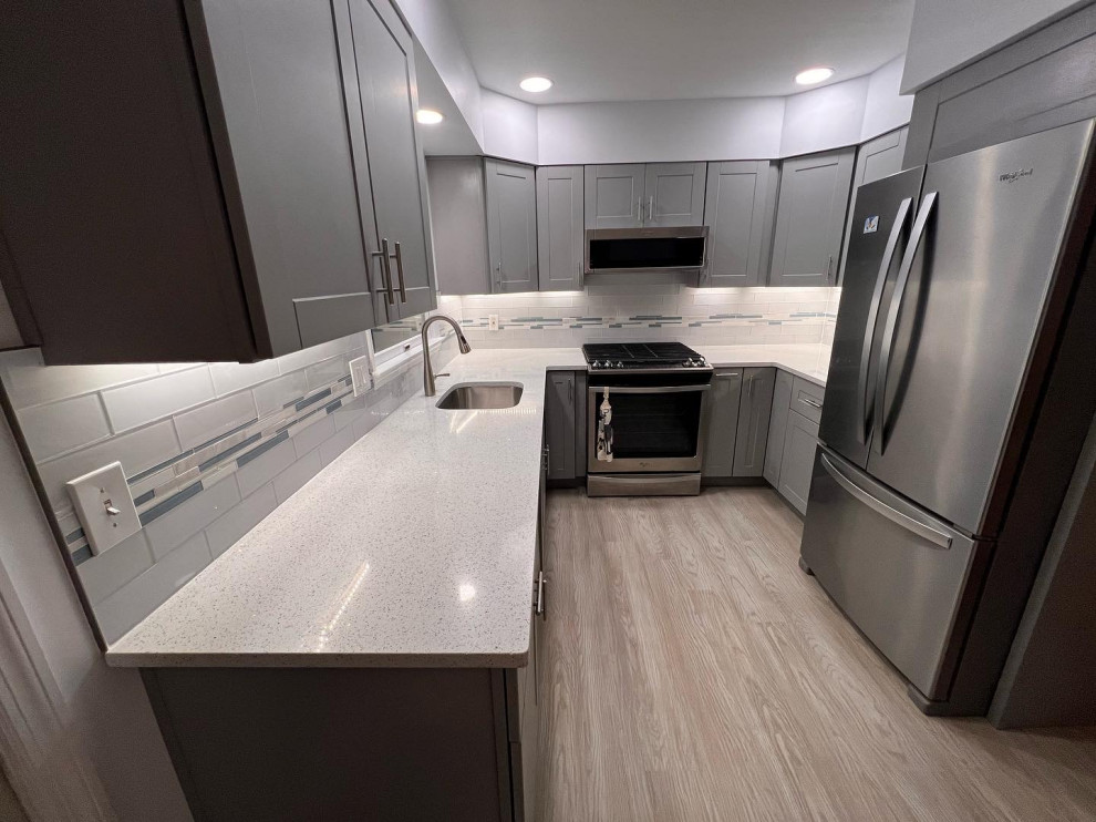 Exempel på ett mellanstort modernt vit vitt kök, med en undermonterad diskho, skåp i shakerstil, grå skåp, bänkskiva i kvarts, vitt stänkskydd, stänkskydd i mosaik, rostfria vitvaror, vinylgolv och brunt golv