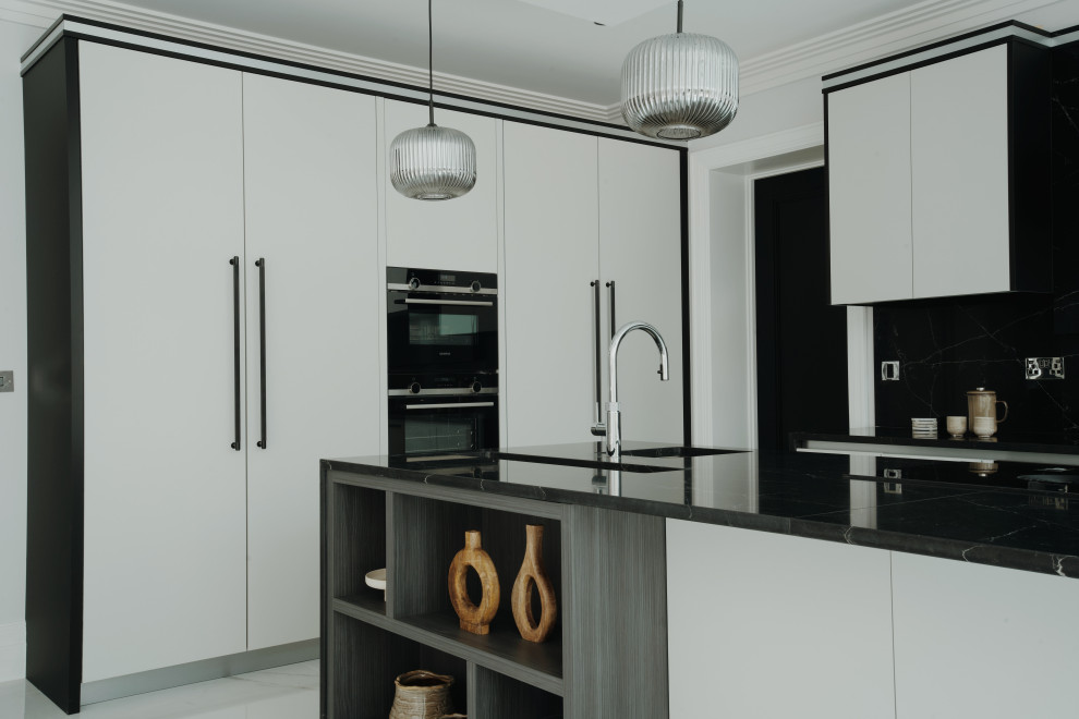 Photo of a large modern grey and black l-shaped kitchen/diner in Surrey with a built-in sink, flat-panel cabinets, grey cabinets, composite countertops, black splashback, engineered quartz splashback, black appliances, porcelain flooring, an island, white floors, black worktops, a coffered ceiling and feature lighting.
