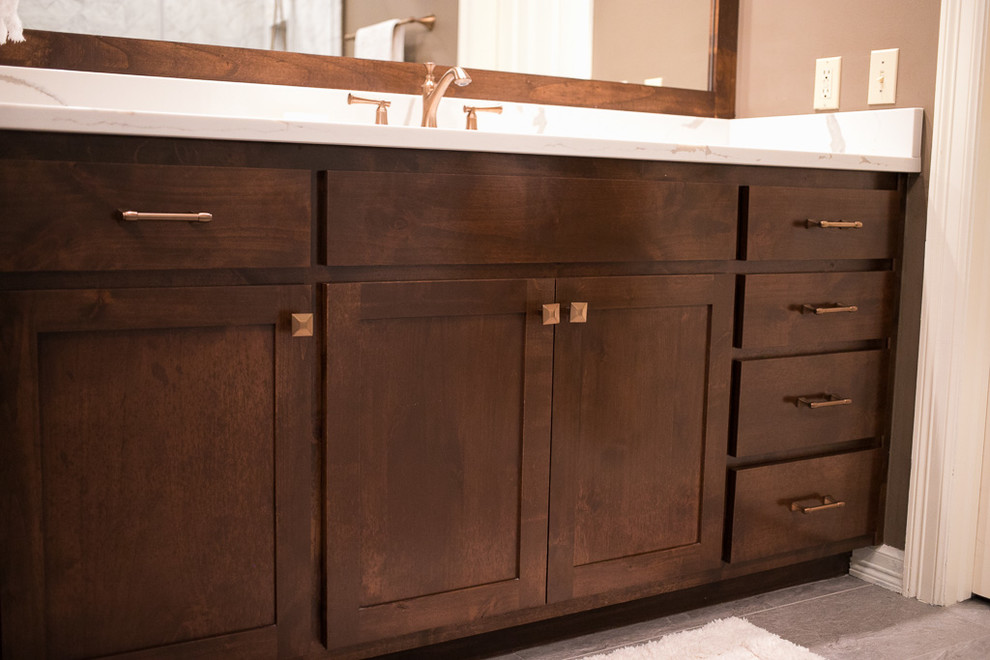 Corner shower - large transitional master white tile and marble tile porcelain tile and gray floor corner shower idea with shaker cabinets, dark wood cabinets, an undermount tub, a one-piece toilet, brown walls, an undermount sink, quartz countertops, a hinged shower door and white countertops