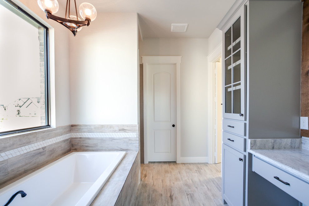 Photo of a large transitional master bathroom in Dallas with shaker cabinets, blue cabinets, a drop-in tub, a curbless shower, beige tile, ceramic tile, beige walls, ceramic floors, an undermount sink, granite benchtops, beige floor and a hinged shower door.