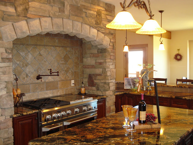 Example of a large mountain style u-shaped medium tone wood floor open concept kitchen design with beaded inset cabinets, dark wood cabinets, granite countertops, beige backsplash, stainless steel appliances and an island