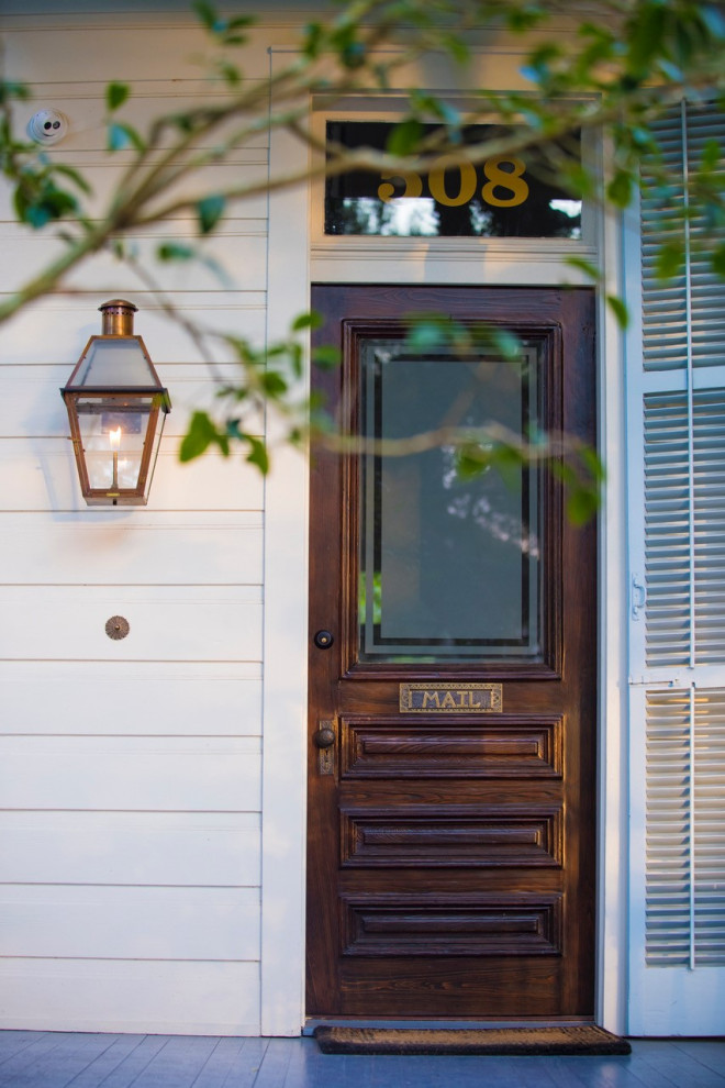 This is an example of a traditional front door in New Orleans with white walls, painted wood floors, a single front door and a dark wood front door.