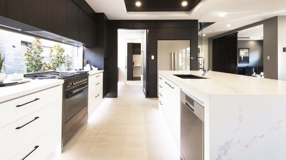 This is an example of a large modern galley open plan kitchen in Sydney with a double-bowl sink, flat-panel cabinets, white cabinets, marble benchtops, white splashback, with island and white benchtop.