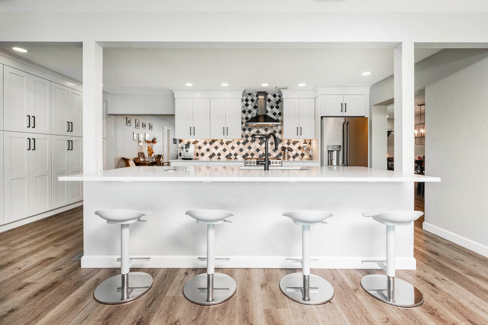 Example of a large transitional vinyl floor and brown floor kitchen pantry design in Orlando with an undermount sink, shaker cabinets, white cabinets, quartzite countertops, multicolored backsplash, porcelain backsplash, stainless steel appliances, an island and white countertops