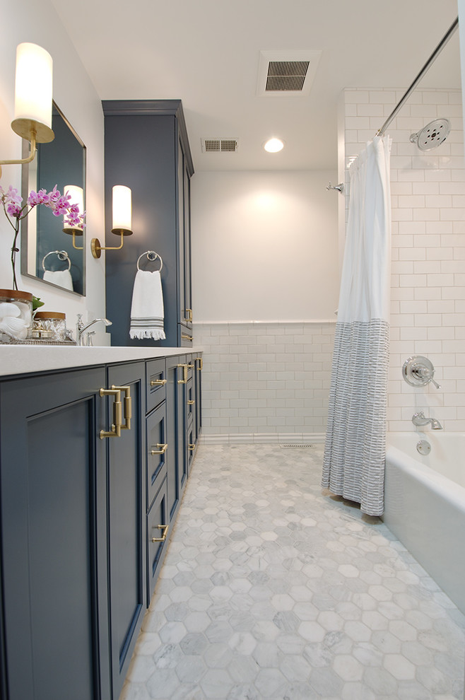 Design ideas for a mid-sized transitional bathroom in Chicago with blue cabinets, an alcove tub, an alcove shower, a two-piece toilet, white tile, ceramic tile, white walls, marble floors, an undermount sink, engineered quartz benchtops, white floor, a shower curtain and recessed-panel cabinets.