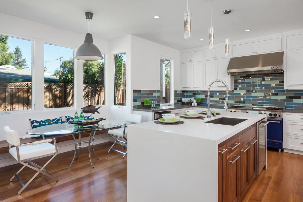 Photo of a beach style eat-in kitchen in San Francisco with an undermount sink, shaker cabinets, white cabinets, multi-coloured splashback, coloured appliances, medium hardwood floors and with island.