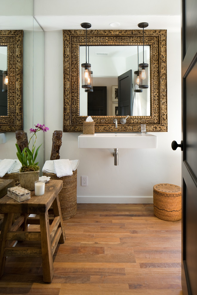 Design ideas for a mid-sized mediterranean powder room in Santa Barbara with a wall-mount sink, white walls and medium hardwood floors.