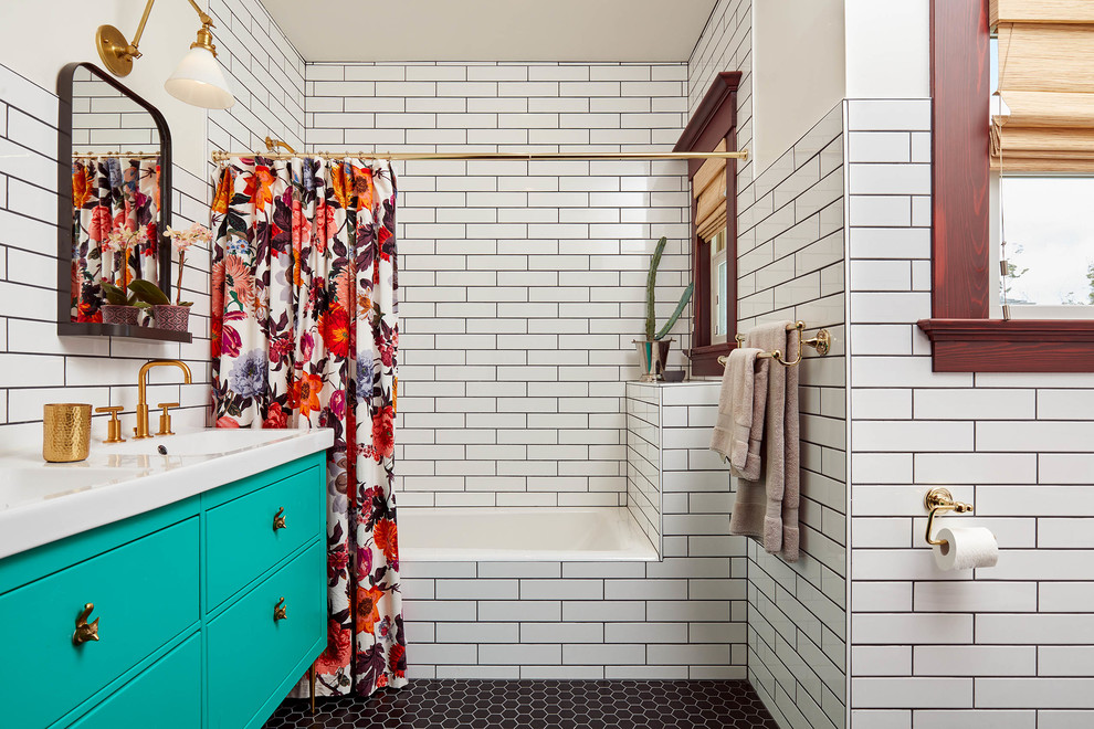 This is an example of a traditional bathroom in San Francisco with blue cabinets, a drop-in tub, a shower/bathtub combo, white tile, subway tile, white walls, an integrated sink, black floor, a shower curtain and flat-panel cabinets.