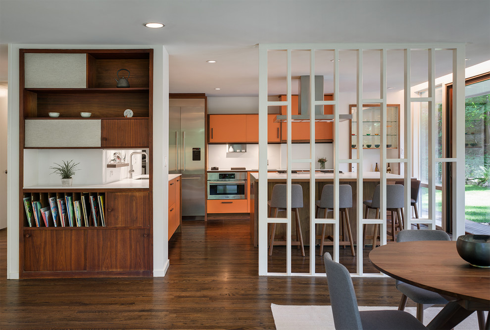 Inspiration for a mid-sized midcentury l-shaped open plan kitchen in New York with an undermount sink, flat-panel cabinets, orange cabinets, white splashback, stainless steel appliances, dark hardwood floors and with island.