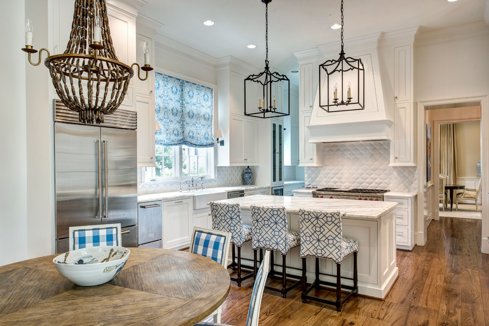 Inspiration for a traditional eat-in kitchen in New Orleans with a farmhouse sink, beaded inset cabinets, white cabinets, white splashback, stainless steel appliances, dark hardwood floors, with island, brown floor and white benchtop.
