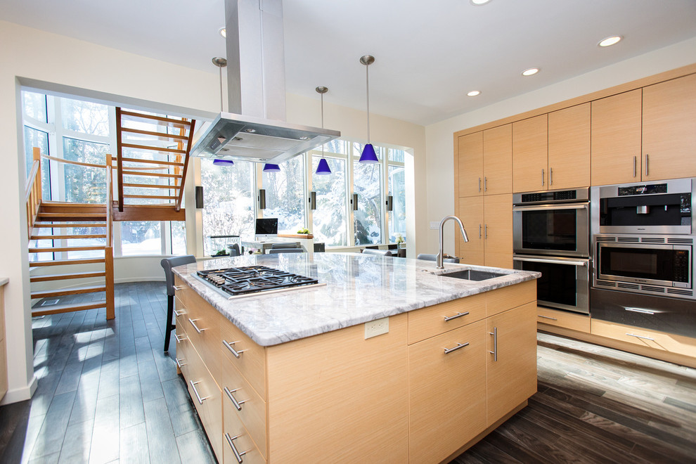 This is an example of a large modern l-shaped open plan kitchen in Boston with a drop-in sink, flat-panel cabinets, light wood cabinets, marble benchtops, multi-coloured splashback, stainless steel appliances, painted wood floors and with island.