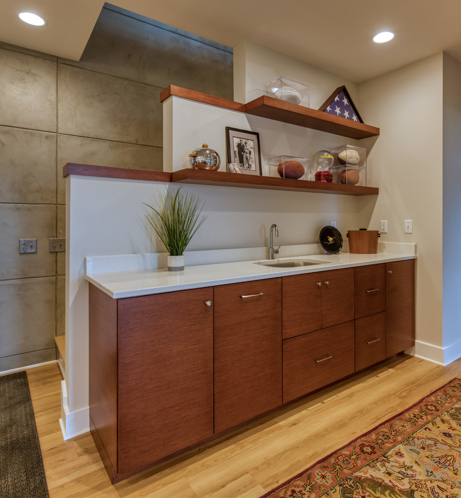 Photo of a small midcentury galley wet bar in Other with an undermount sink, flat-panel cabinets, medium wood cabinets, quartz benchtops, white splashback, laminate floors and white benchtop.