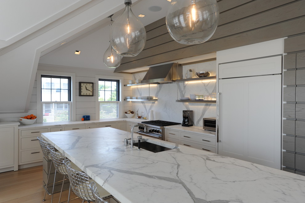 Design ideas for a beach style l-shaped kitchen in Boston with an undermount sink, flat-panel cabinets, white cabinets, white splashback and panelled appliances.