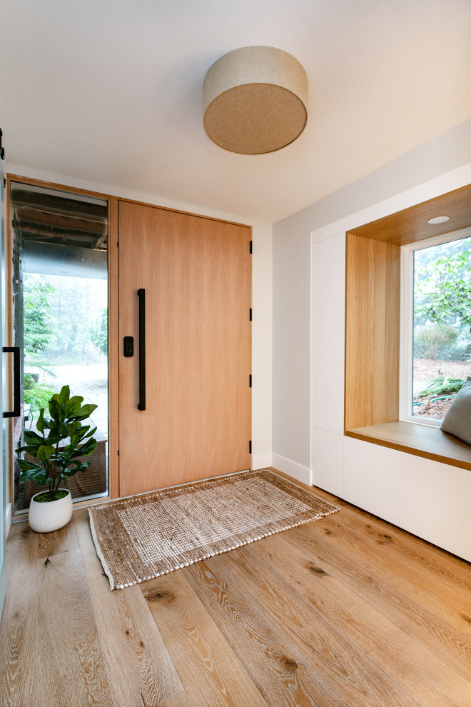 Idées déco pour un hall d'entrée scandinave de taille moyenne avec un mur gris, un sol en bois brun, une porte simple, une porte en bois clair et un sol marron.