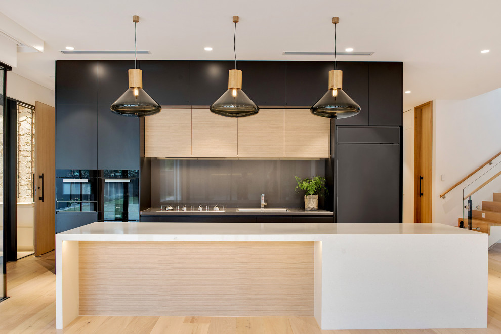 Design ideas for a large contemporary galley kitchen in Adelaide with an integrated sink, flat-panel cabinets, black cabinets, grey splashback, glass sheet splashback, panelled appliances, with island, beige floor and beige benchtop.