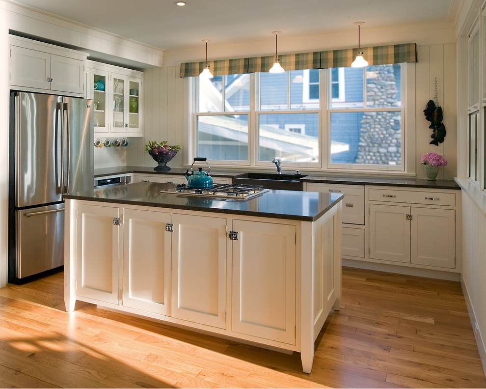 This is an example of a mid-sized traditional u-shaped eat-in kitchen in Detroit with a farmhouse sink, glass-front cabinets, white cabinets, quartz benchtops, white splashback, stainless steel appliances, light hardwood floors and with island.