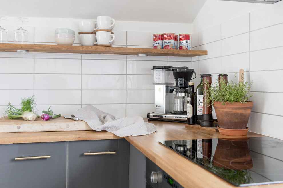 Inspiration for a mid-sized scandinavian l-shaped separate kitchen in Gothenburg with a drop-in sink, flat-panel cabinets, grey cabinets, wood benchtops, white splashback, ceramic splashback, stainless steel appliances, light hardwood floors and no island.