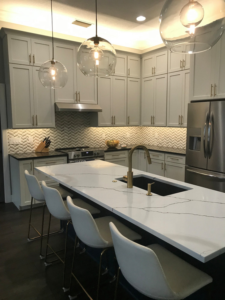 Expansive transitional l-shaped open plan kitchen in Baltimore with an undermount sink, shaker cabinets, white cabinets, quartz benchtops, white splashback, marble splashback, stainless steel appliances, vinyl floors, with island, brown floor and multi-coloured benchtop.