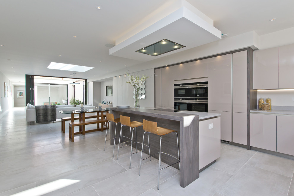 Mid-sized contemporary l-shaped eat-in kitchen in London with a double-bowl sink, flat-panel cabinets, beige cabinets, quartzite benchtops, stainless steel appliances, marble floors, with island and white floor.