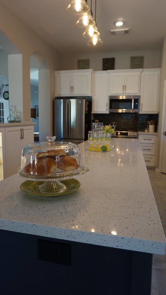 Klassische Küche mit Quarzwerkstein-Arbeitsplatte, Küchenrückwand in Grau, Rückwand aus Glasfliesen, Porzellan-Bodenfliesen und Kücheninsel in Houston