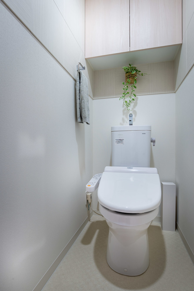 Mid-sized scandinavian powder room in Other with beaded inset cabinets, light wood cabinets, a one-piece toilet, beige tile, ceramic tile, white walls, vinyl floors, an integrated sink and white floor.
