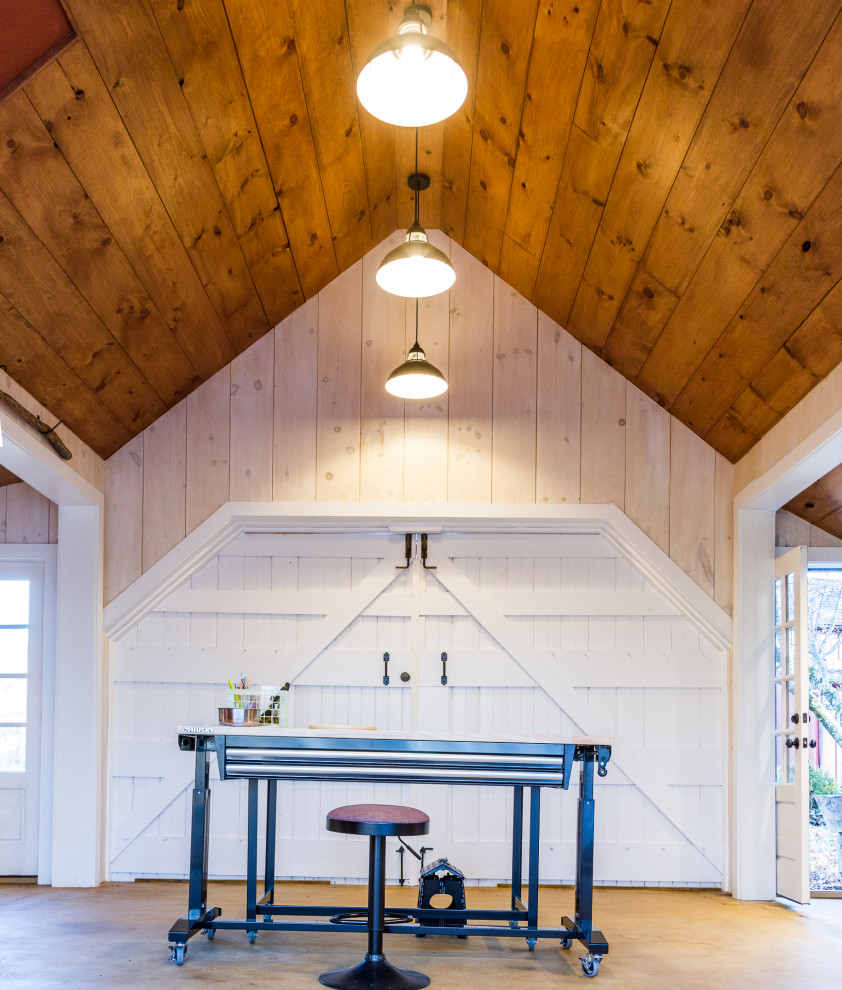 Mittelgroßes Landhaus Arbeitszimmer ohne Kamin mit Studio, weißer Wandfarbe, Betonboden, freistehendem Schreibtisch, freigelegten Dachbalken und Holzdielenwänden in Philadelphia