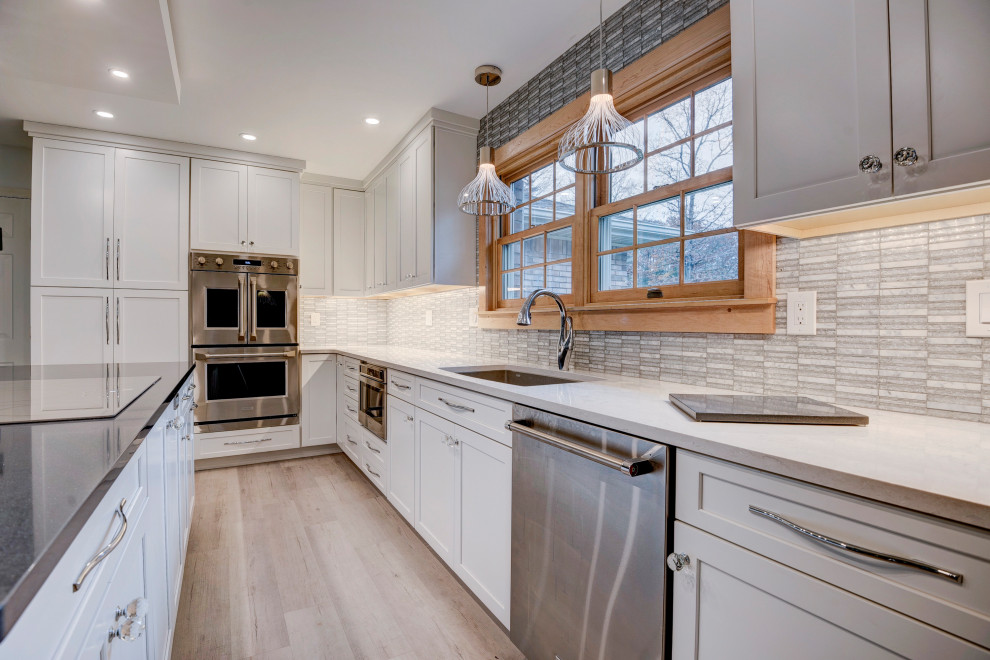 Open concept kitchen - large transitional u-shaped light wood floor and beige floor open concept kitchen idea in New York with an undermount sink, shaker cabinets, white cabinets, quartzite countertops, white backsplash, ceramic backsplash, stainless steel appliances, an island and white countertops