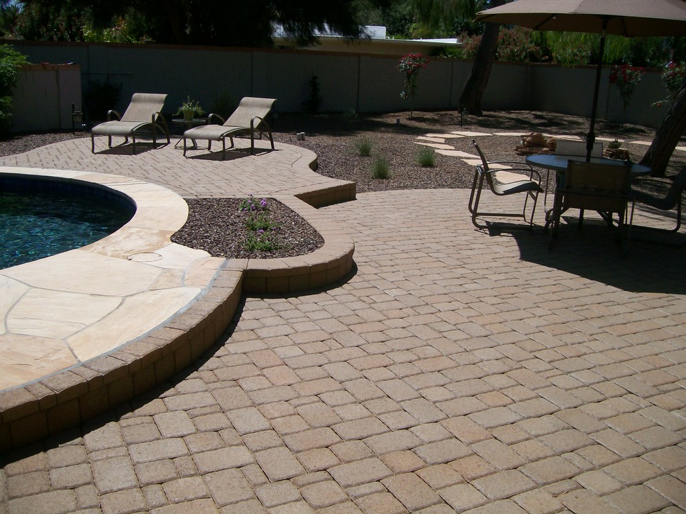 Example of a transitional backyard brick and custom-shaped pool design in Phoenix