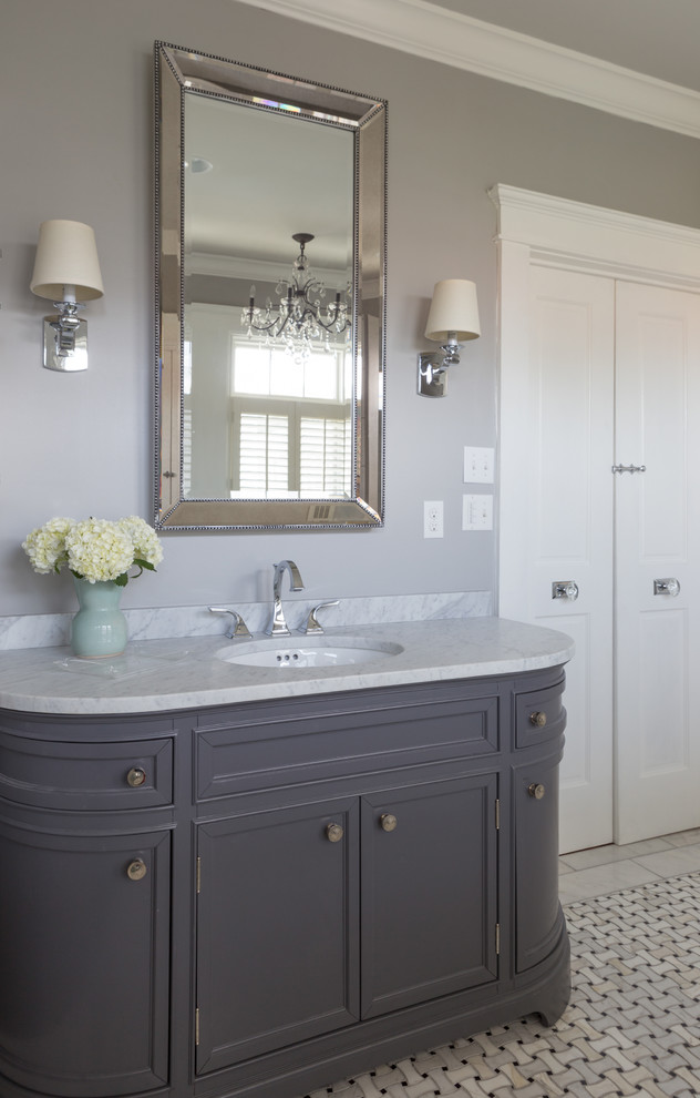 Photo of a large traditional master bathroom in New Orleans with an undermount sink, furniture-like cabinets, grey cabinets, onyx benchtops, a freestanding tub, a corner shower, a two-piece toilet, black and white tile, mosaic tile, grey walls and marble floors.