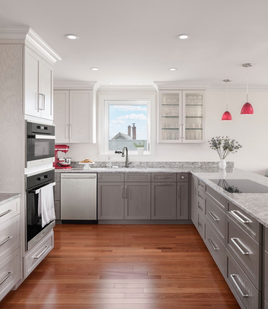 Design ideas for a mid-sized transitional u-shaped kitchen in Portland Maine with an undermount sink, glass-front cabinets, grey cabinets, granite benchtops, granite splashback, stainless steel appliances, medium hardwood floors, with island and grey benchtop.