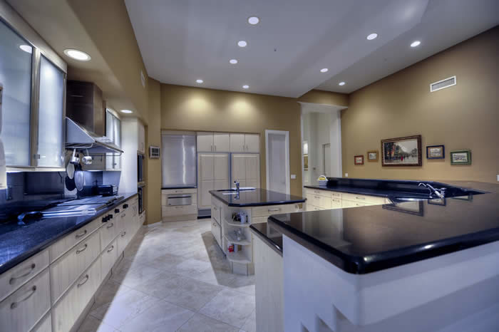 Photo of an expansive traditional u-shaped open plan kitchen in Phoenix with a drop-in sink, raised-panel cabinets, medium wood cabinets, granite benchtops, black splashback, stone slab splashback, stainless steel appliances, travertine floors and with island.