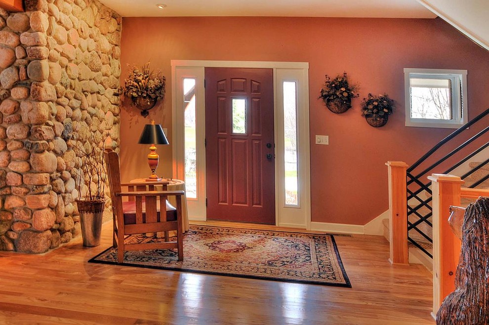 Mid-sized mountain style medium tone wood floor foyer photo in Milwaukee with brown walls and a metal front door